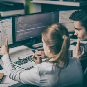 woman pointing to computer monitor with male looking on